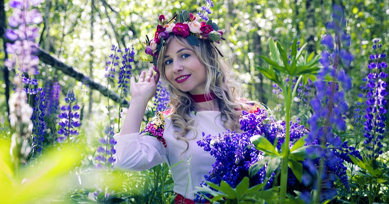 Молодая женщина, находящаяся в лесистой местности, окруженной цветами люпина Традиции ситцевой свадьбы