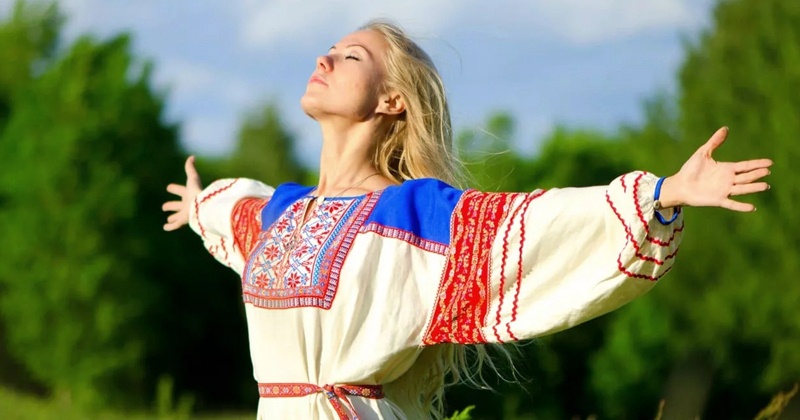Женщина с длинными светлыми волосами, стоящая на фоне зелени и неба Традиции Бумажной свадьбы